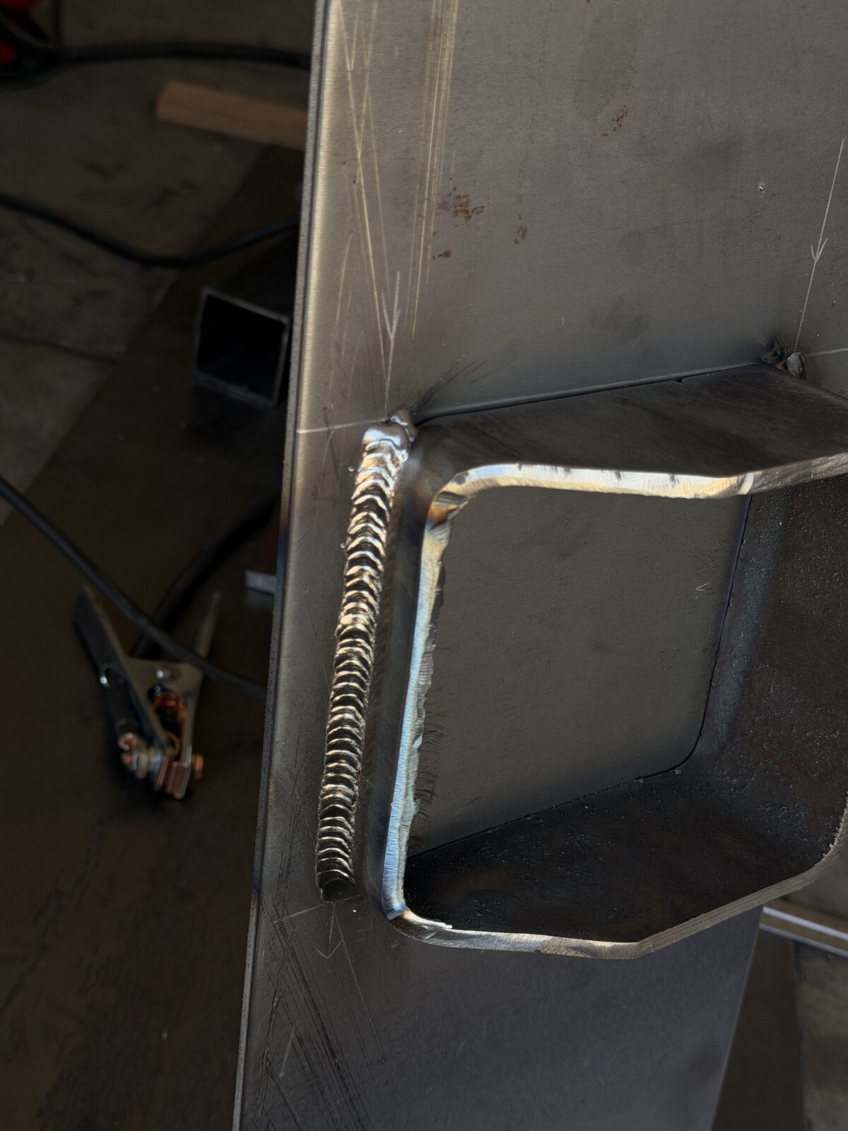 Close-up of a clean stacked weld bead joining a steel staircase stringer plate