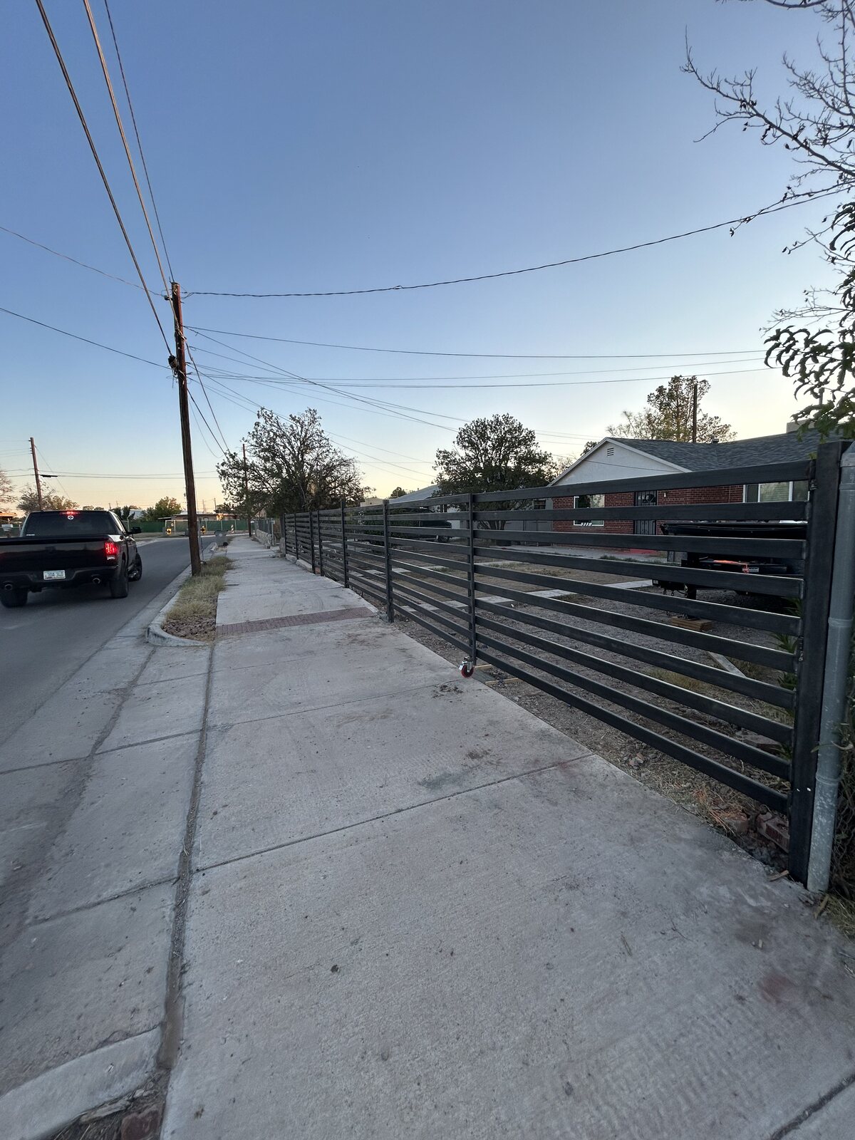 Horizontal slat steel rolling driveway gate at dusk