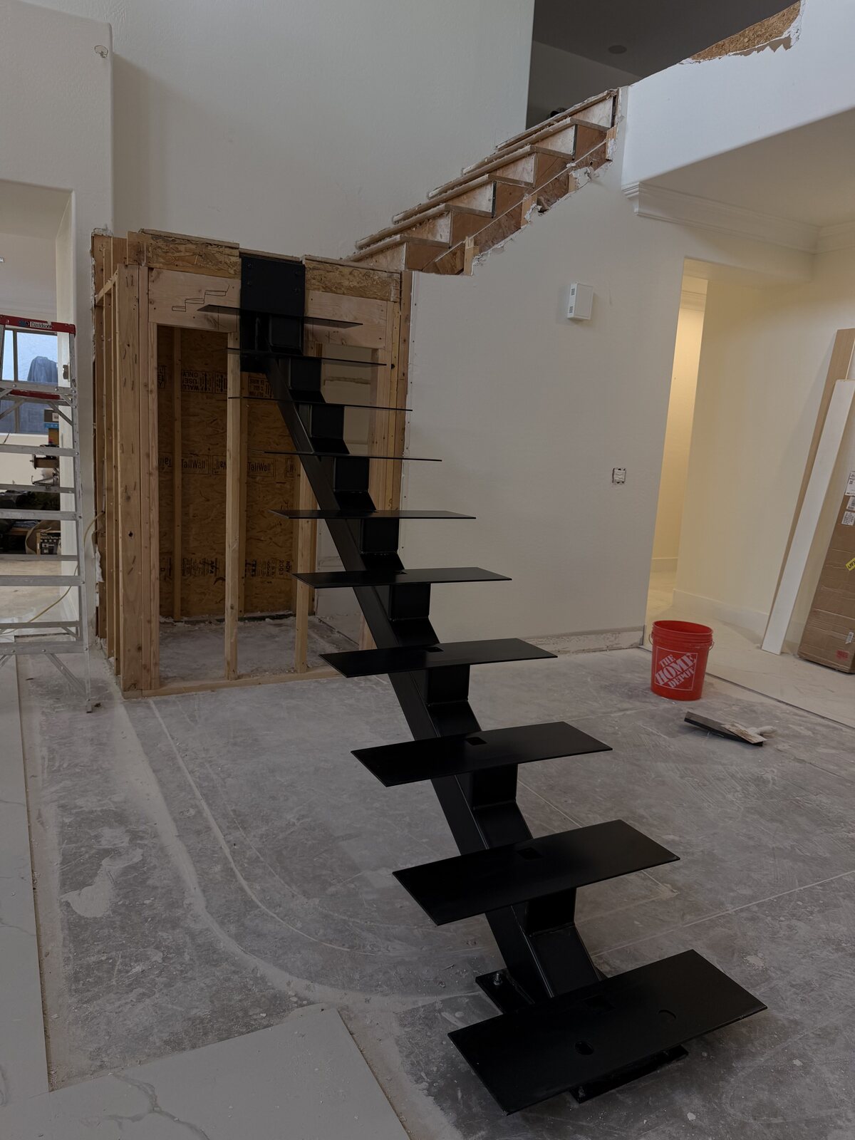 Black mono-stringer floating steel staircase installed in a home