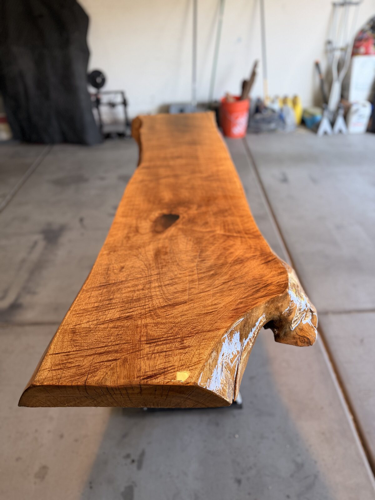 Long mesquite live-edge slab sanded and sealed on the shop floor