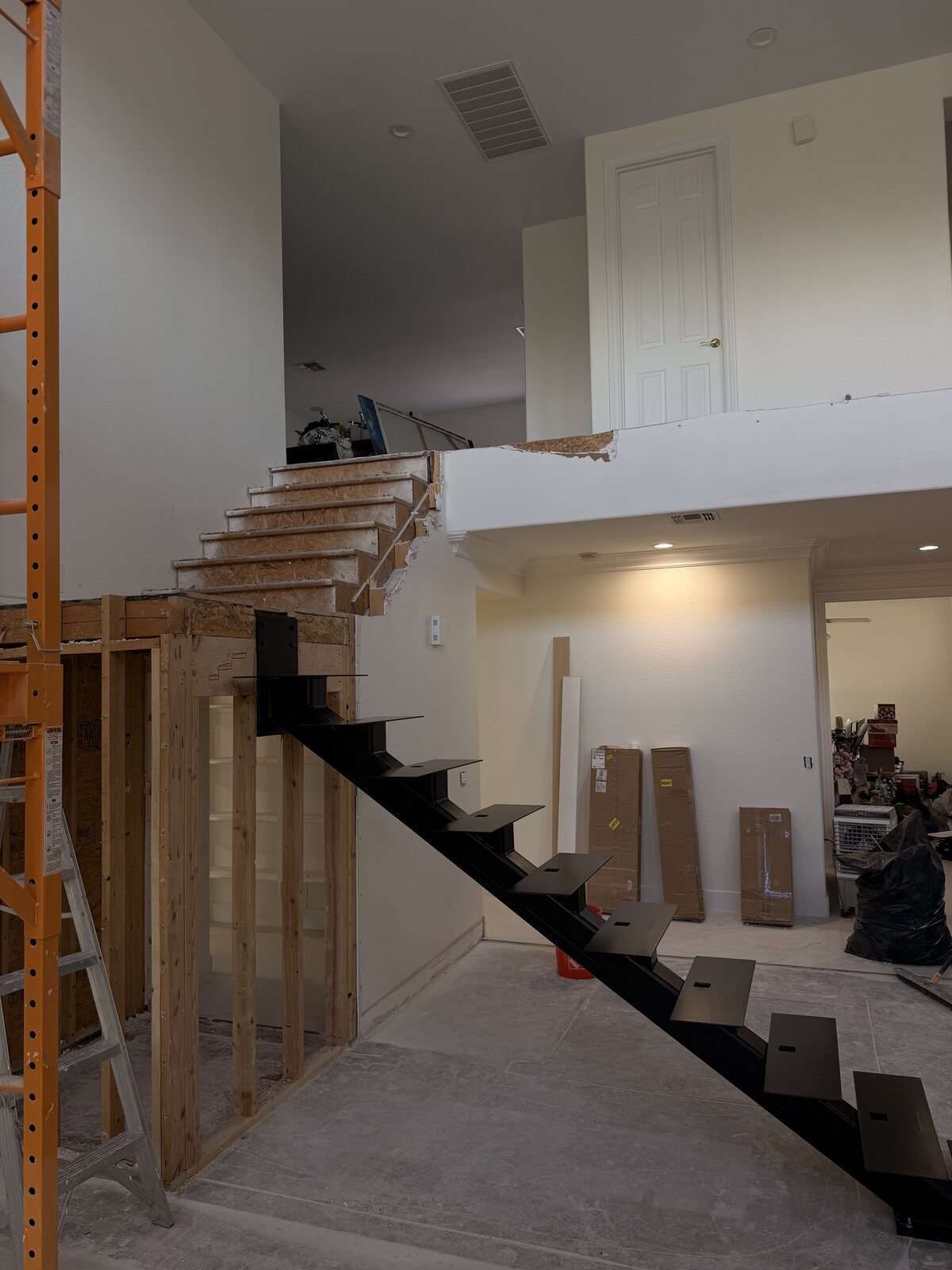 Black steel mono-stringer staircase installed inside a home during remodel